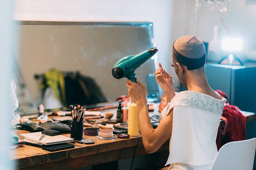 Drag performer applying makeup with various products